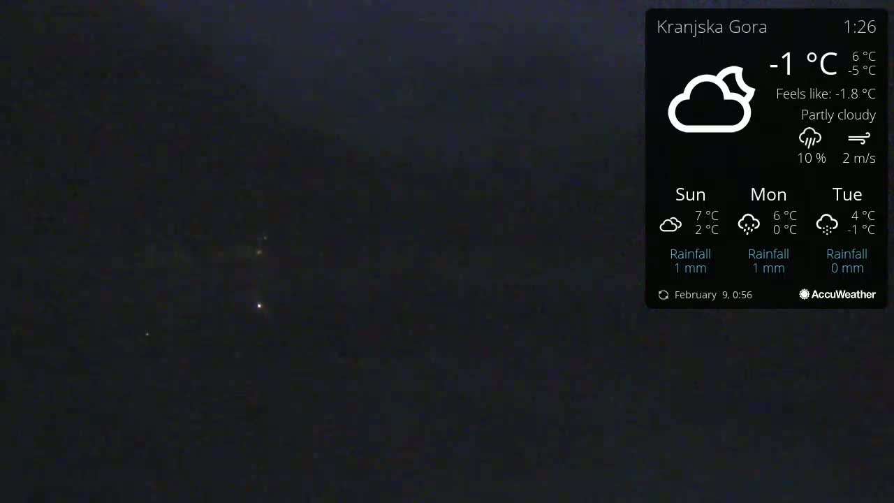 A nighttime outdoor scene under a partly cloudy sky shows a few distant lights.