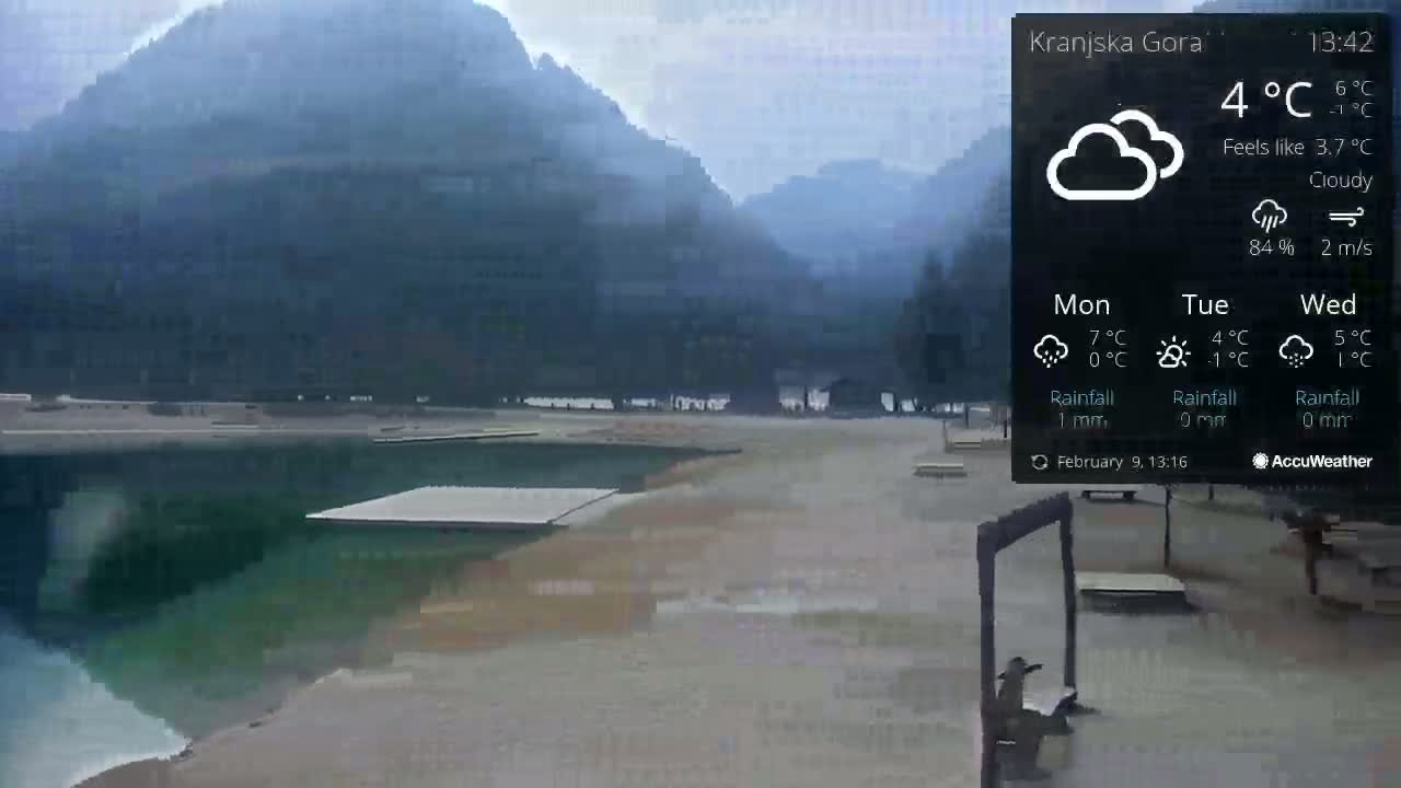 A cloudy day shows a mostly empty lakeside area with mountains in the background.