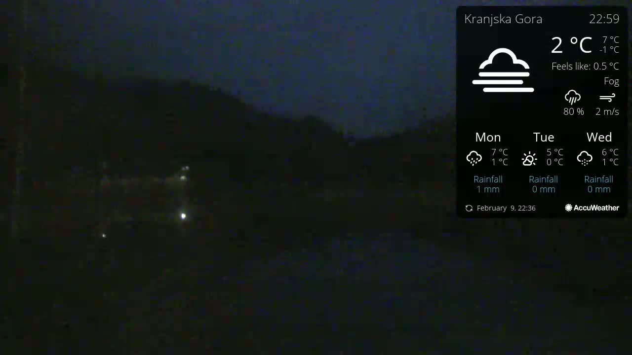 A dark, foggy night scene shows dimly lit areas with a hill in the background.