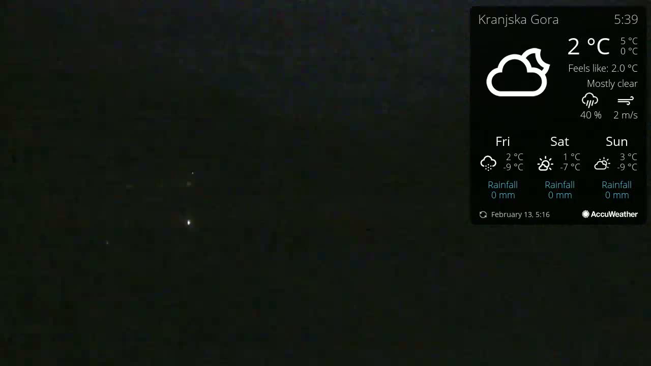 A mostly clear night scene shows a few distant lights under a dark sky.