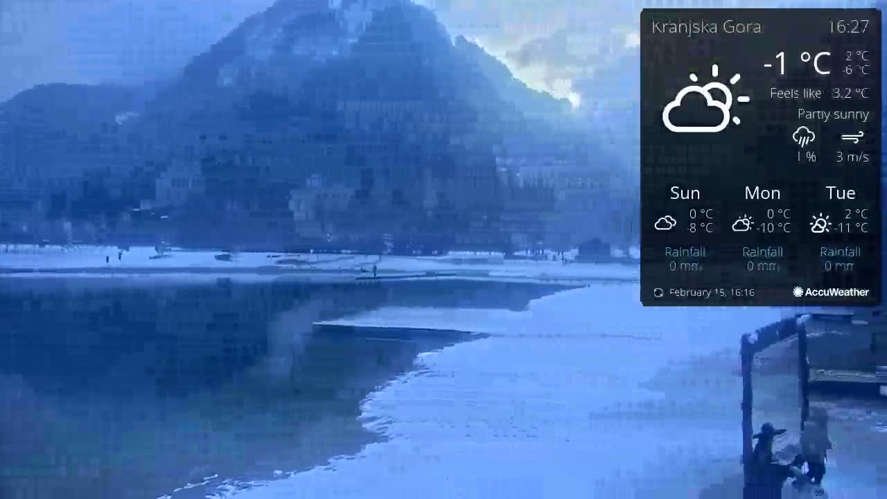 A partly sunny, cold day with a temperature of -1°C shows a snow-covered waterfront area and town nestled below a hill.