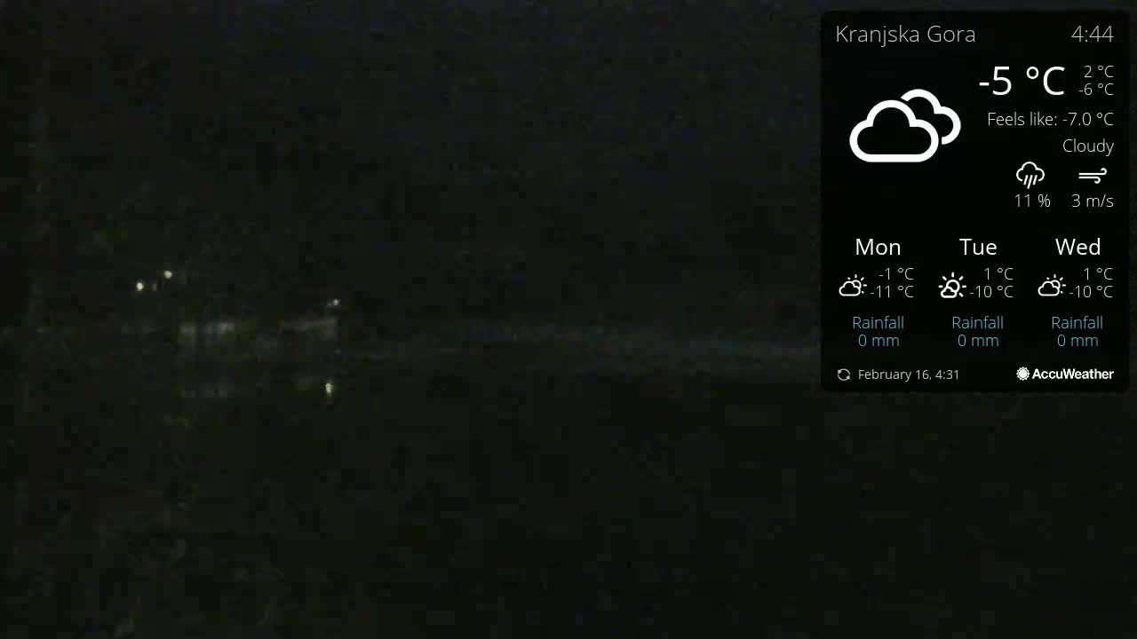 A dark, nighttime scene of a body of water with faint lights visible in the distance under cloudy conditions.