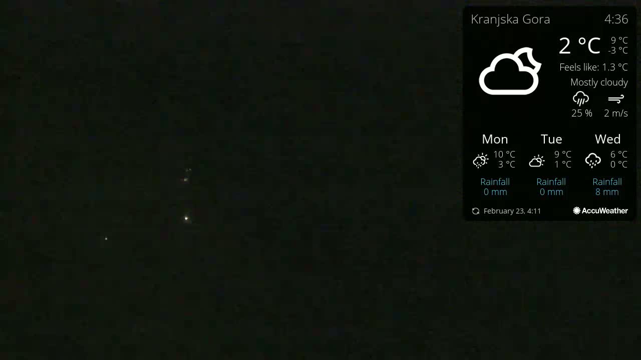 A mostly cloudy night sky with a few distant lights visible.