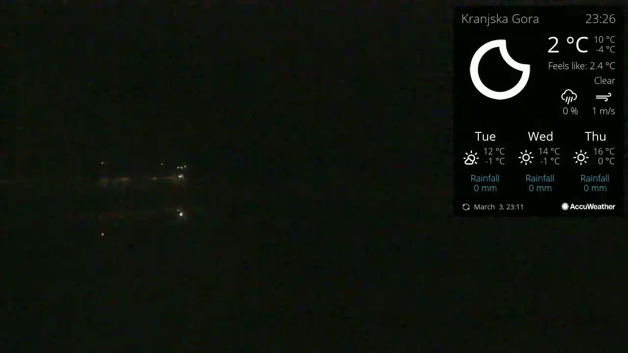 A dark, nighttime outdoor scene shows a few distant lights, under clear skies.