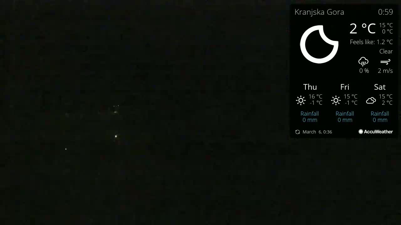 A dark, nighttime scene shows a few distant lights under a clear sky.