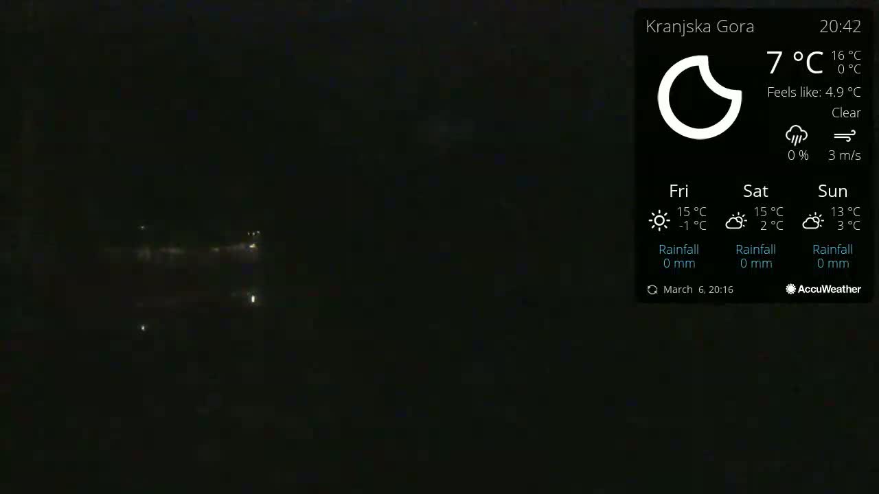 A dark, nighttime scene shows a few distant lights under a clear sky.