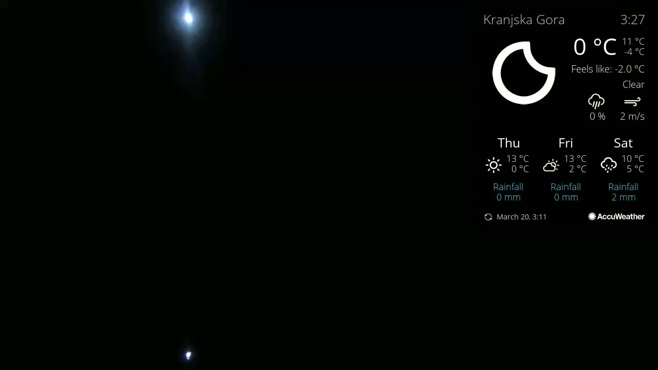 A dark, nighttime scene shows two bright lights, possibly from a distant source, in a clear sky.