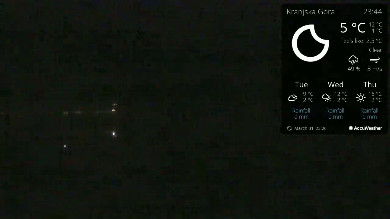 A dark nighttime scene shows a few distant lights under a clear sky.