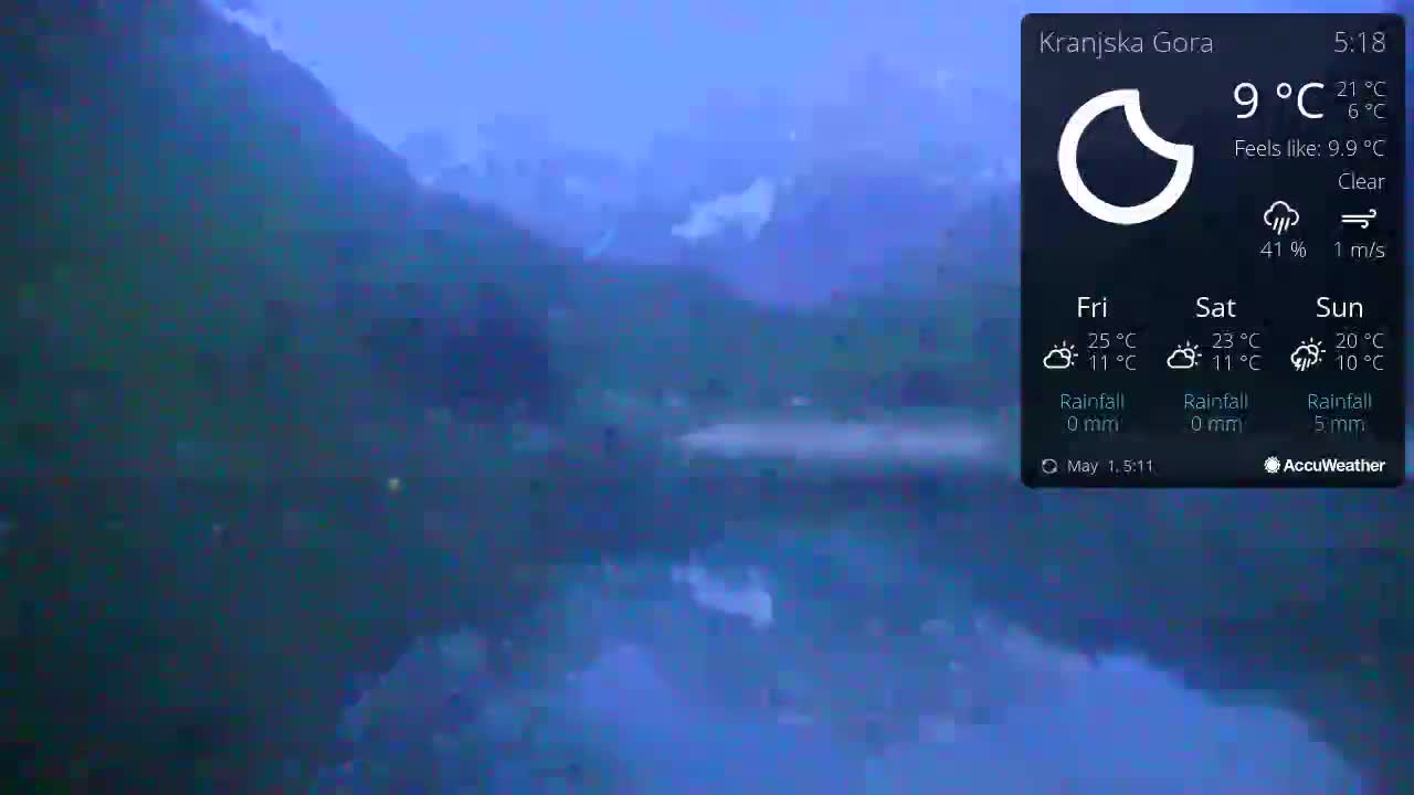 A calm lake reflects dark mountains under a clear, twilight sky.