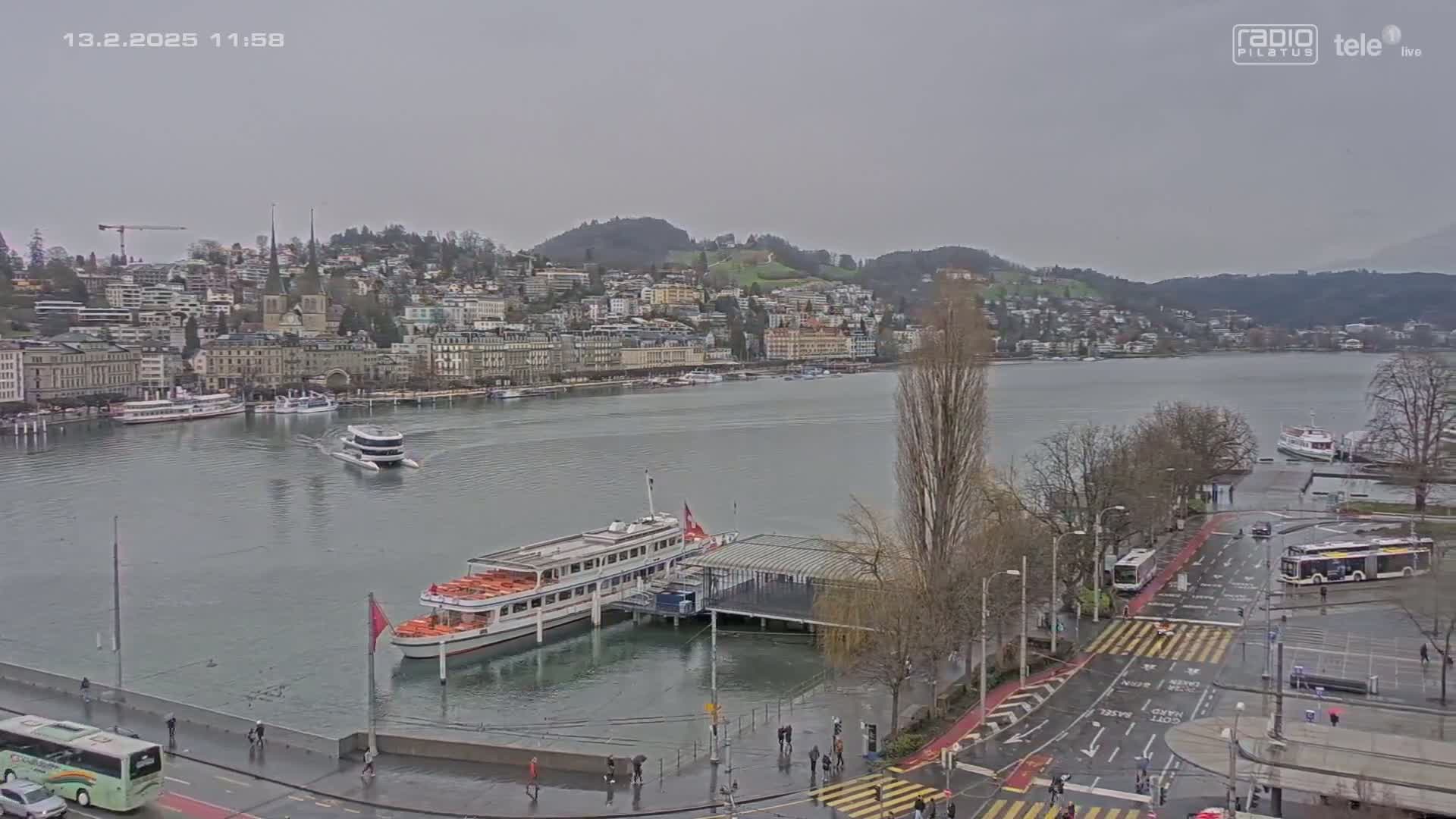 A lakeside city with several buildings and boats is seen on an overcast day with rain.