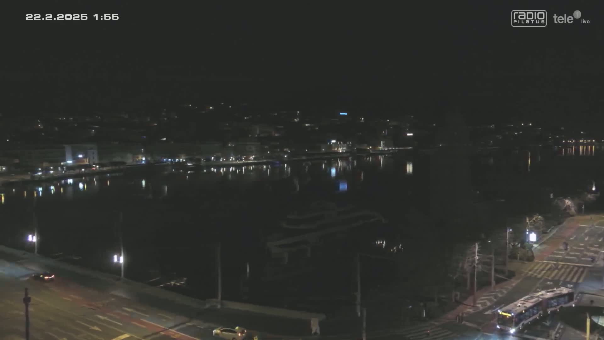 A nighttime view of a calm body of water reflecting a city skyline under a dark sky.