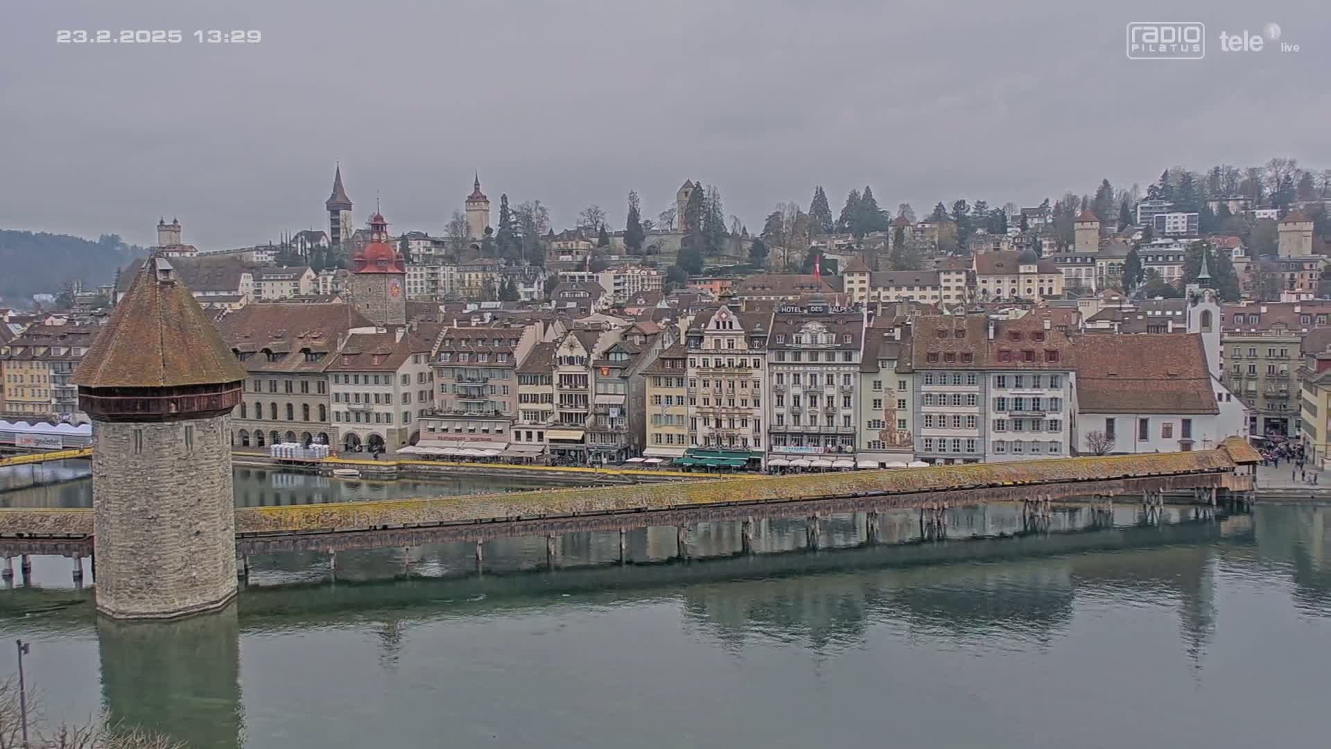 A waterside town with many buildings and a covered bridge, viewed on an overcast day.