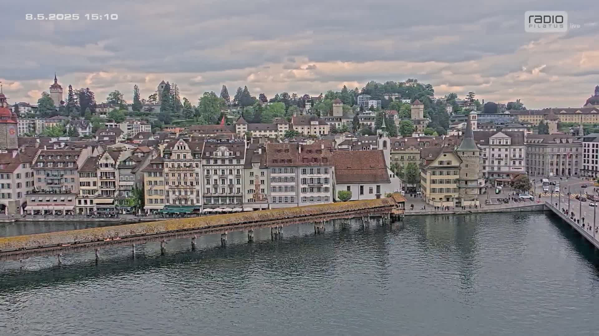A cityscape of numerous buildings along a river under a cloudy sky.