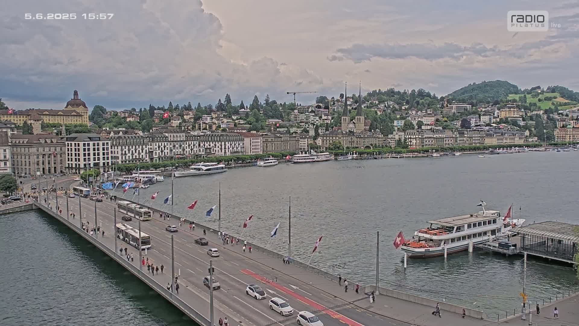 A bridge over a body of water with a city skyline and several boats under partly cloudy skies.