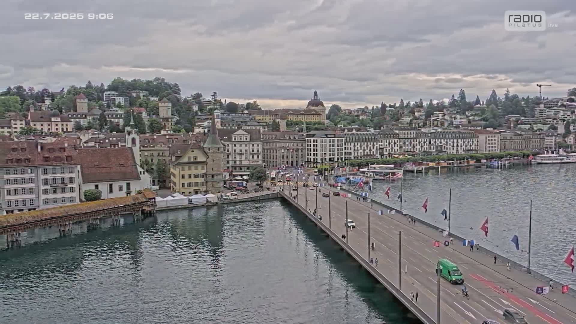 A long bridge stretches across a body of water toward a city with many buildings under an overcast sky.