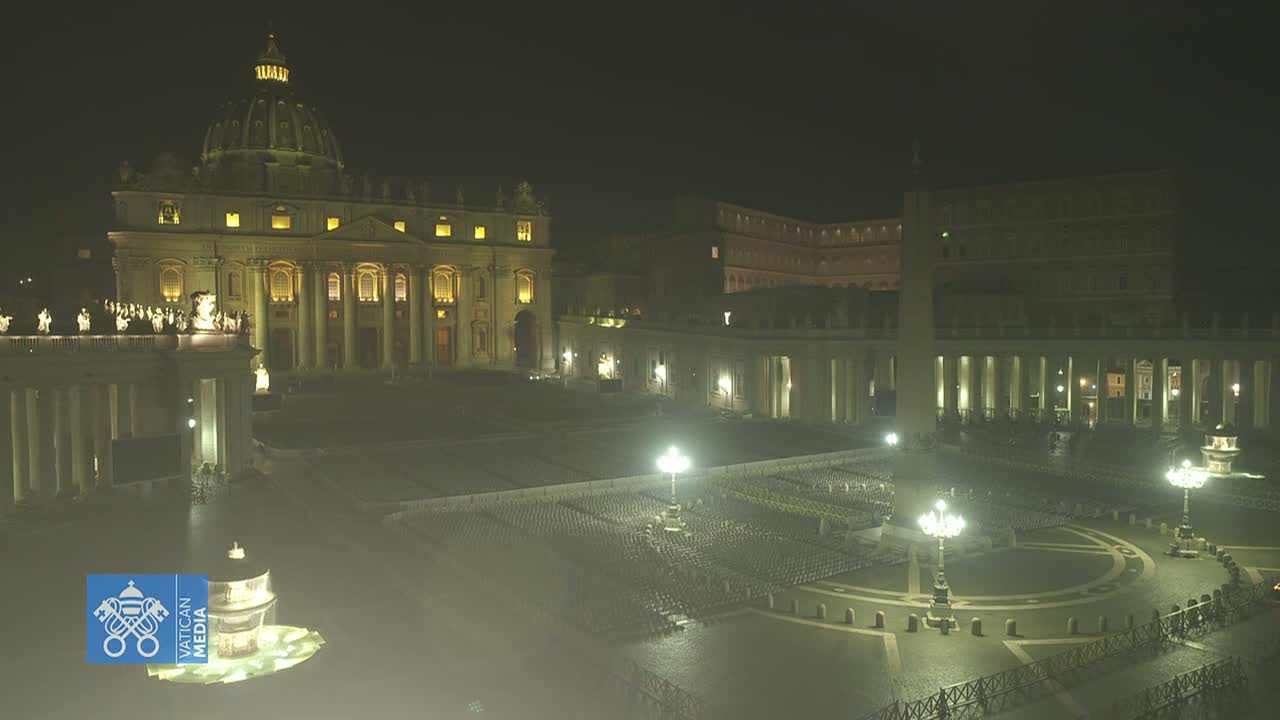 A brightly lit St. Peter's Basilica and square at night, under a dark sky.