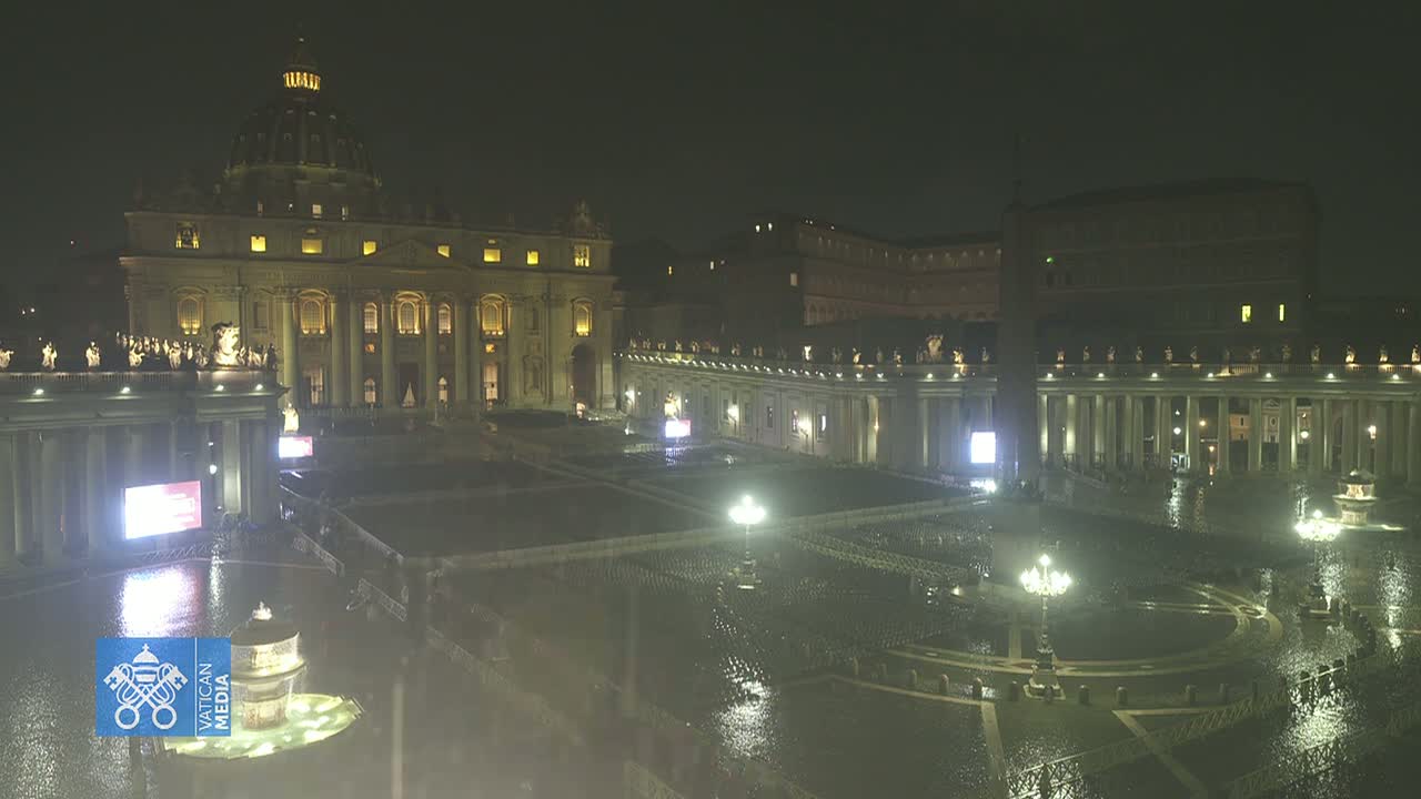 A nighttime view of St. Peter's Basilica and Square in the rain, illuminated by lights.