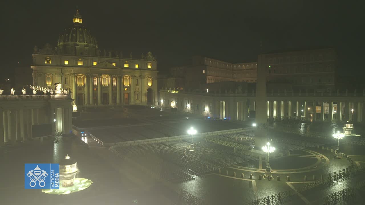 A nighttime, wet view of St. Peter's Basilica and St. Peter's Square, illuminated by artificial light.