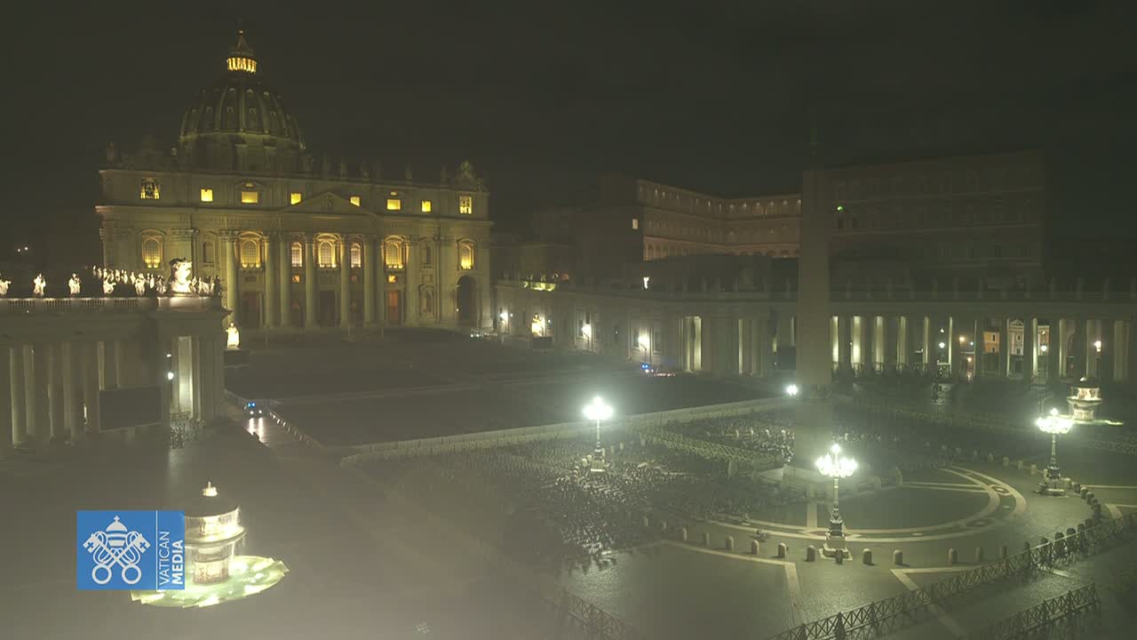 St. Peter's Basilica and St. Peter's Square at night, illuminated, with a large gathering of people in the square.
