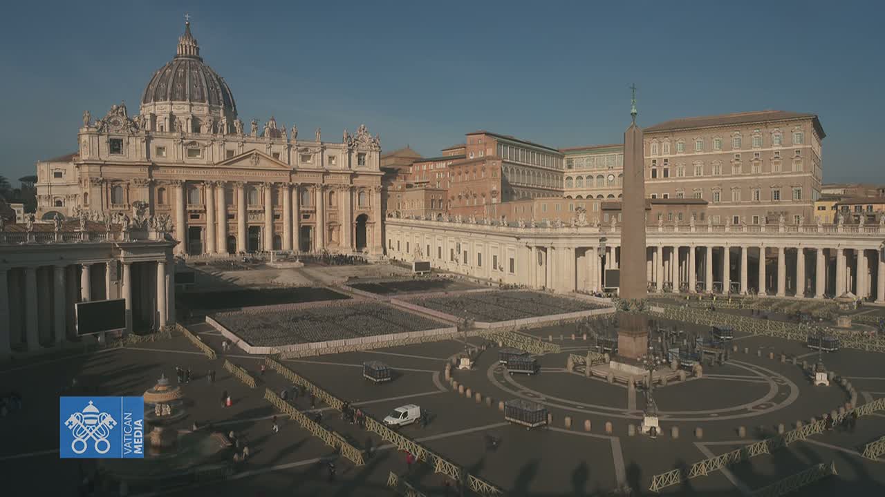 St. Peter's Basilica and St. Peter's Square in Vatican City are shown on a sunny day, with the square mostly empty except for some barriers and a few people.