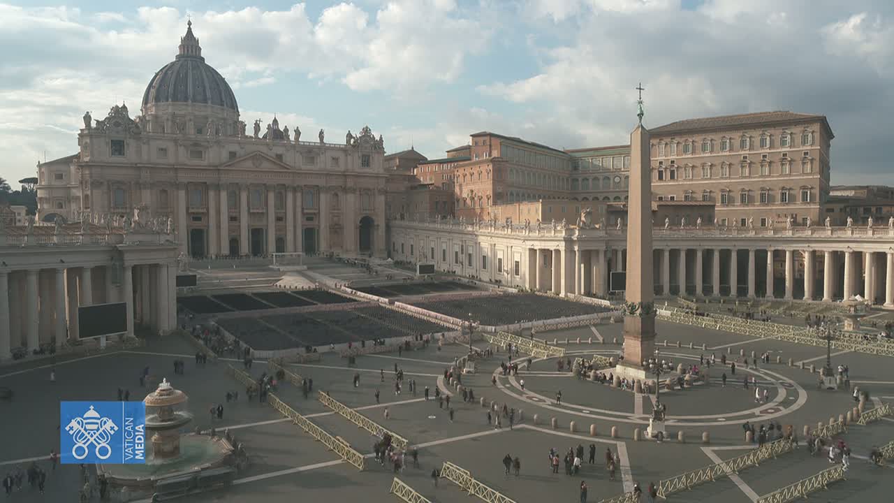 St. Peter's Basilica and St. Peter's Square are shown on a partly cloudy day, with a large number of people sparsely spread across the square.
