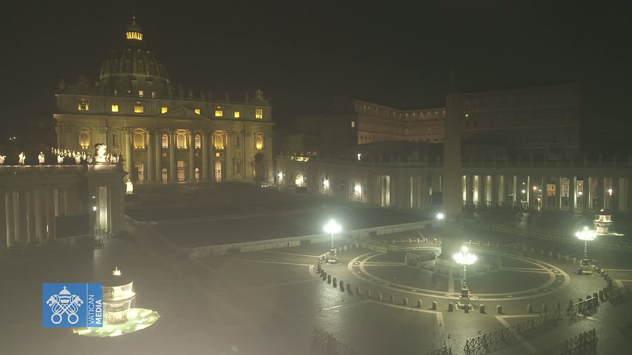 St. Peter's Basilica and St. Peter's Square are illuminated at night, with a slight haze or mist in the air.
