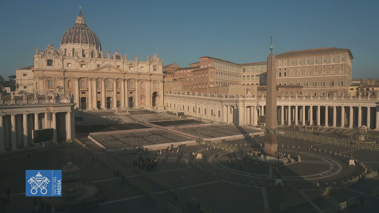 St. Peter's Basilica and St. Peter's Square in Vatican City are shown on a sunny day, with long shadows cast across the large plaza.