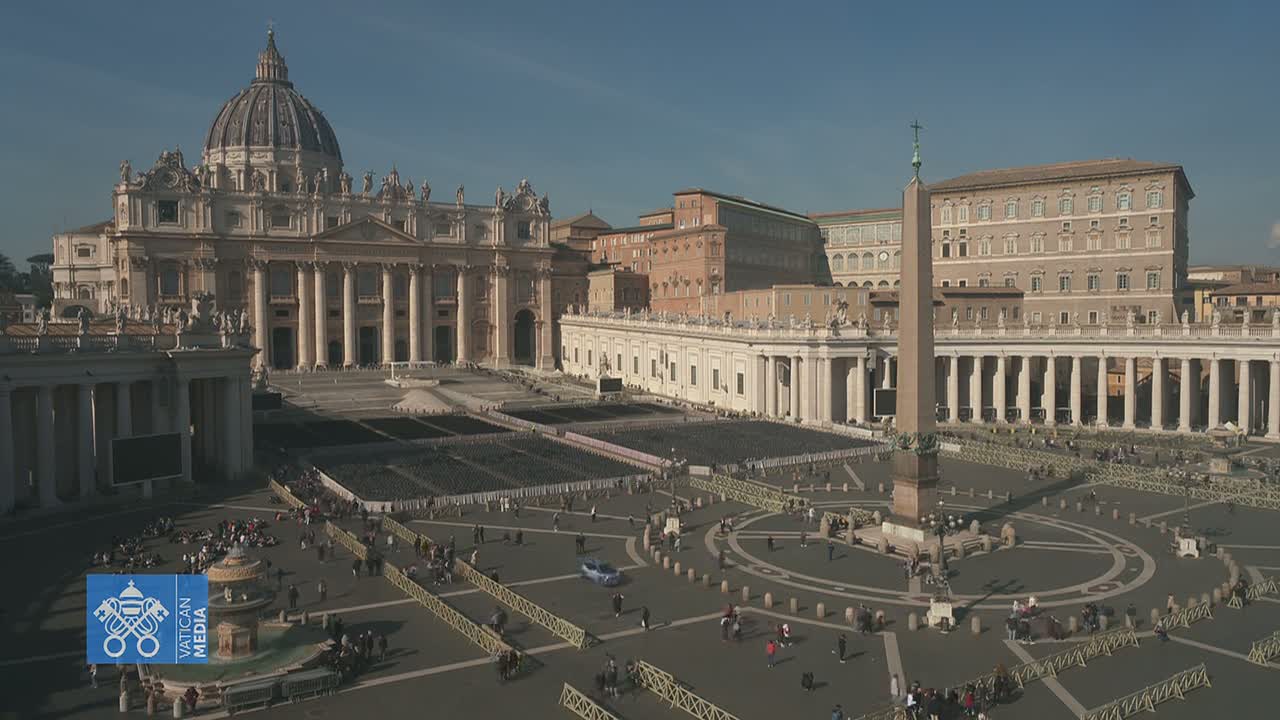 St. Peter's Basilica and Square in Vatican City, under a clear, sunny sky, are shown from an aerial perspective, with a relatively small number of people scattered throughout the large plaza.