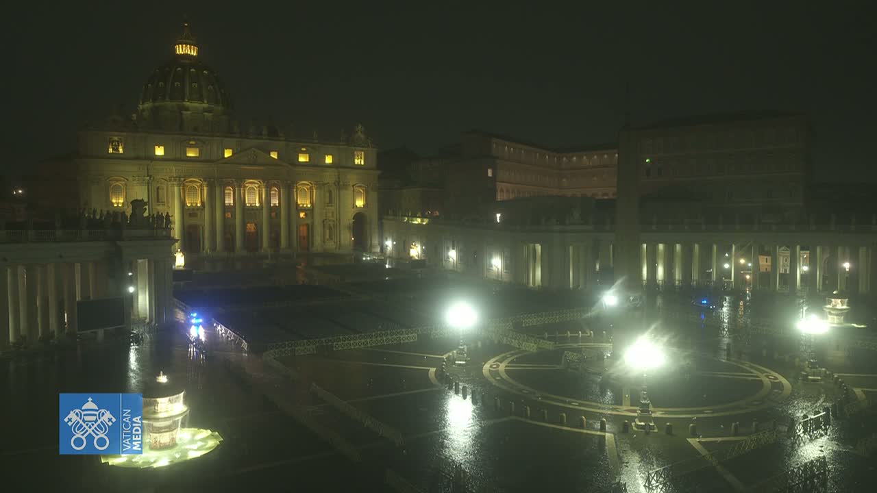 St. Peter's Basilica and St. Peter's Square at night in the rain, illuminated by artificial light.