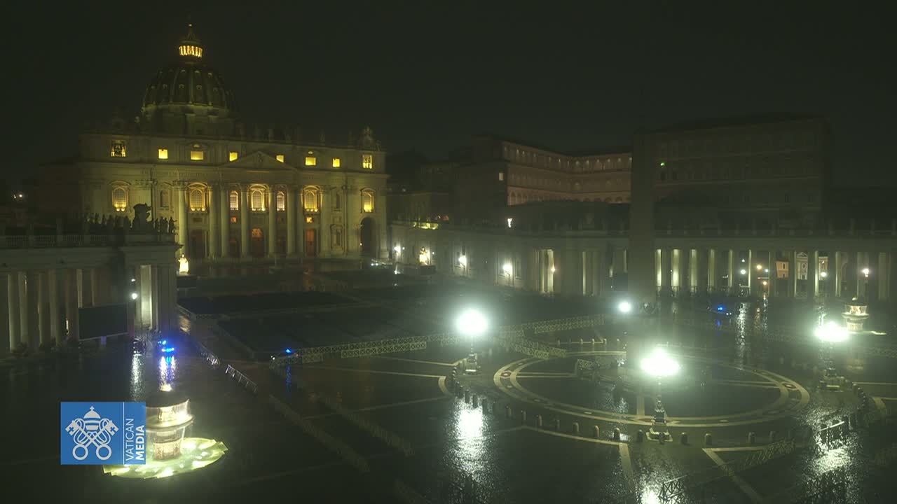 St. Peter's Basilica and St. Peter's Square at night in the rain, illuminated by lights.