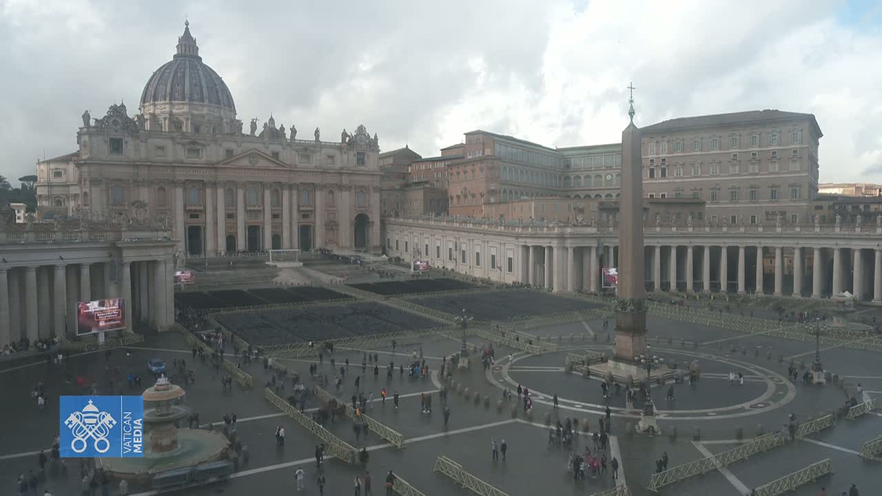 St. Peter's Basilica and St. Peter's Square in Vatican City on an overcast day, with many people sparsely scattered throughout the square.
