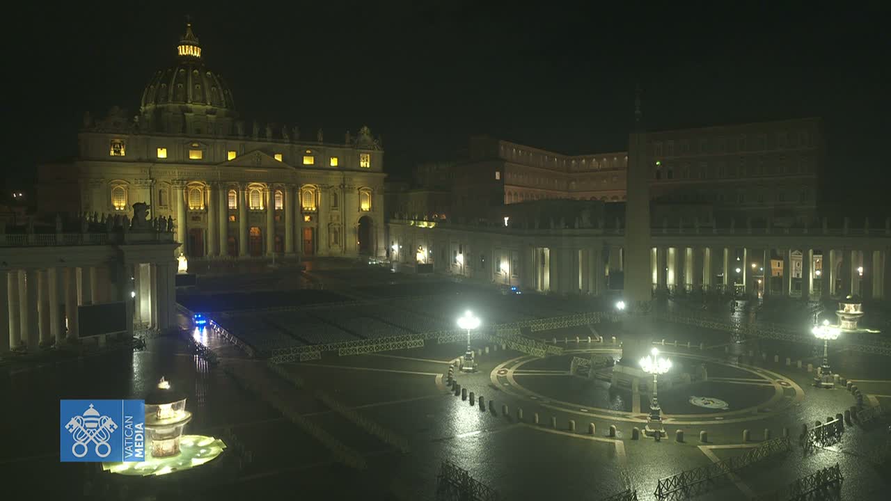 St. Peter's Basilica and Square are illuminated at night under a wet, dark sky.