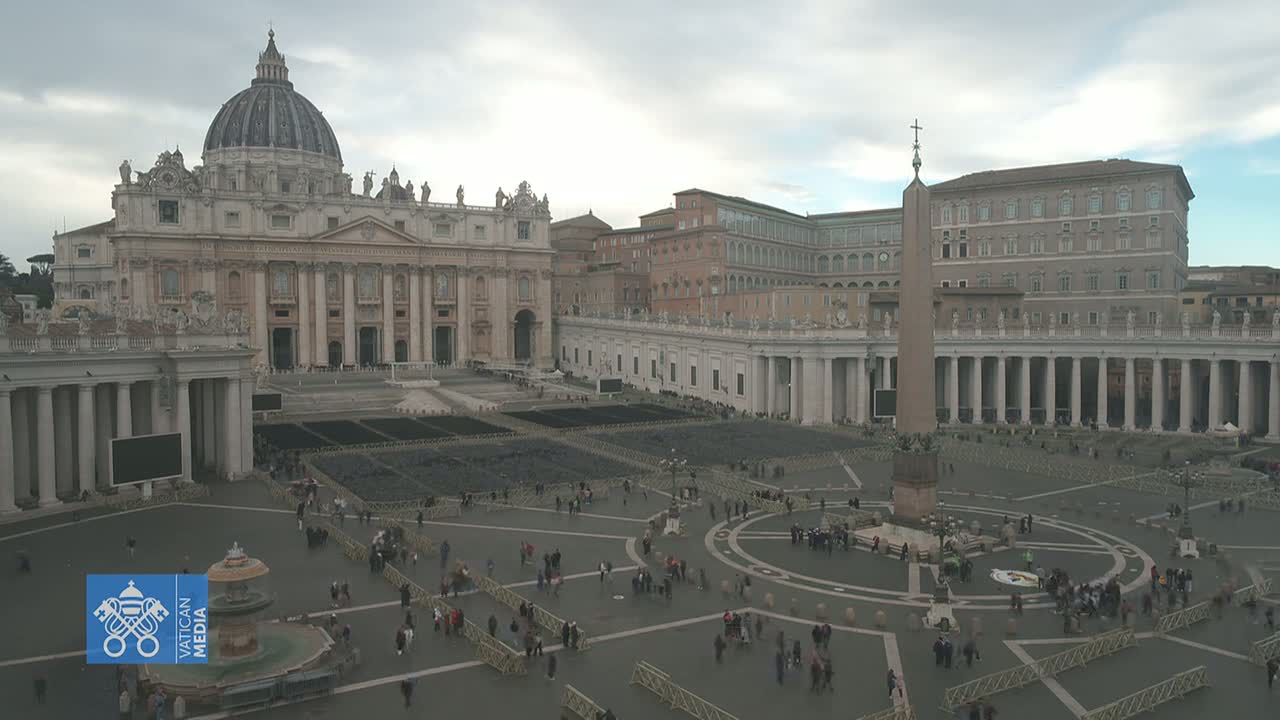 A large, mostly empty plaza with St. Peter's Basilica and other Vatican City buildings visible under an overcast sky.