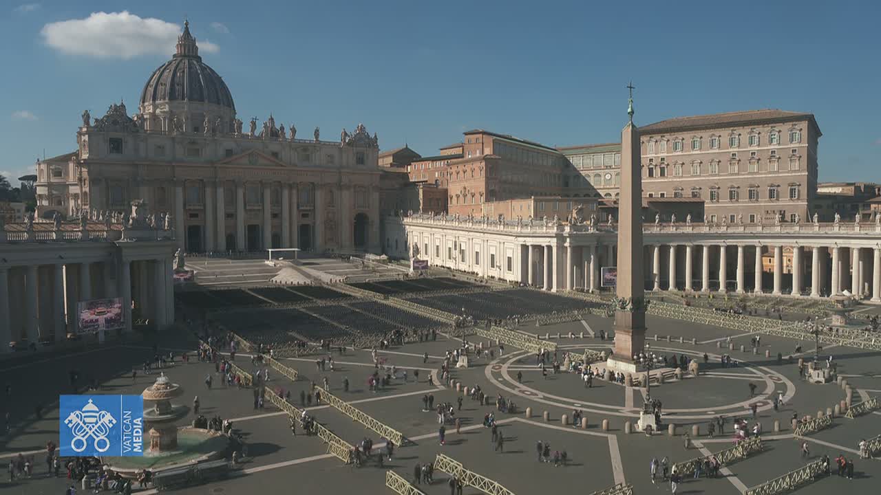 St. Peter's Square in Vatican City, under a clear sky, is filled with many people and rows of chairs surrounding an obelisk.