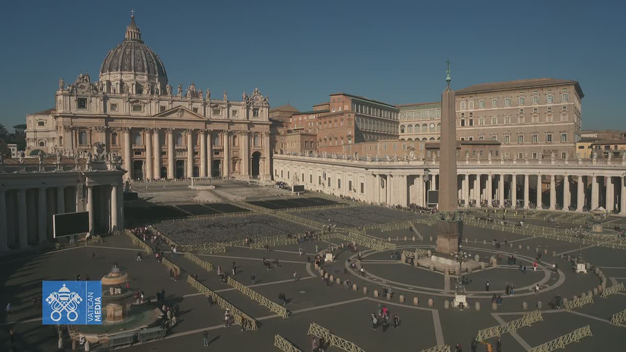 St. Peter's Basilica and St. Peter's Square in Vatican City are shown on a sunny day with many people sparsely scattered throughout the square, which is partially sectioned off by barriers.