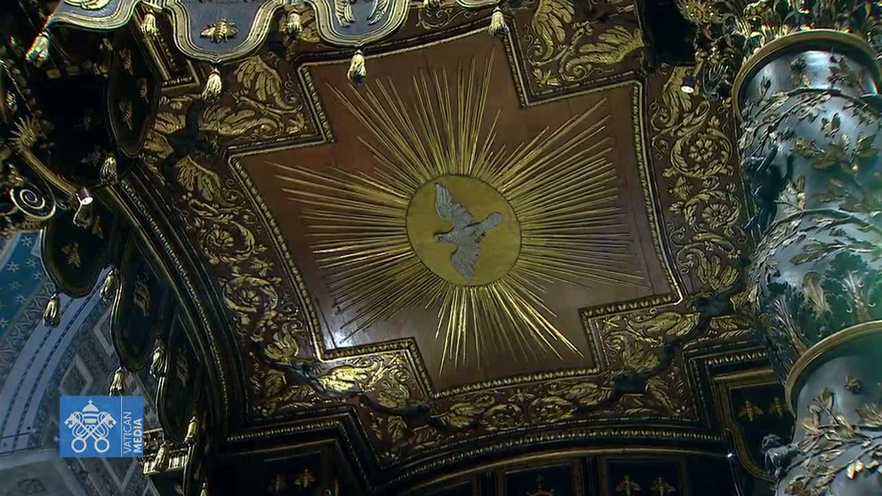 An ornate, dark-wood ceiling with gold detailing, featuring a central image of a dove within a sunburst.