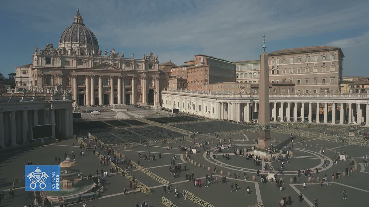 St. Peter's Basilica and St. Peter's Square in Vatican City are shown on a sunny day with many people scattered throughout the square.