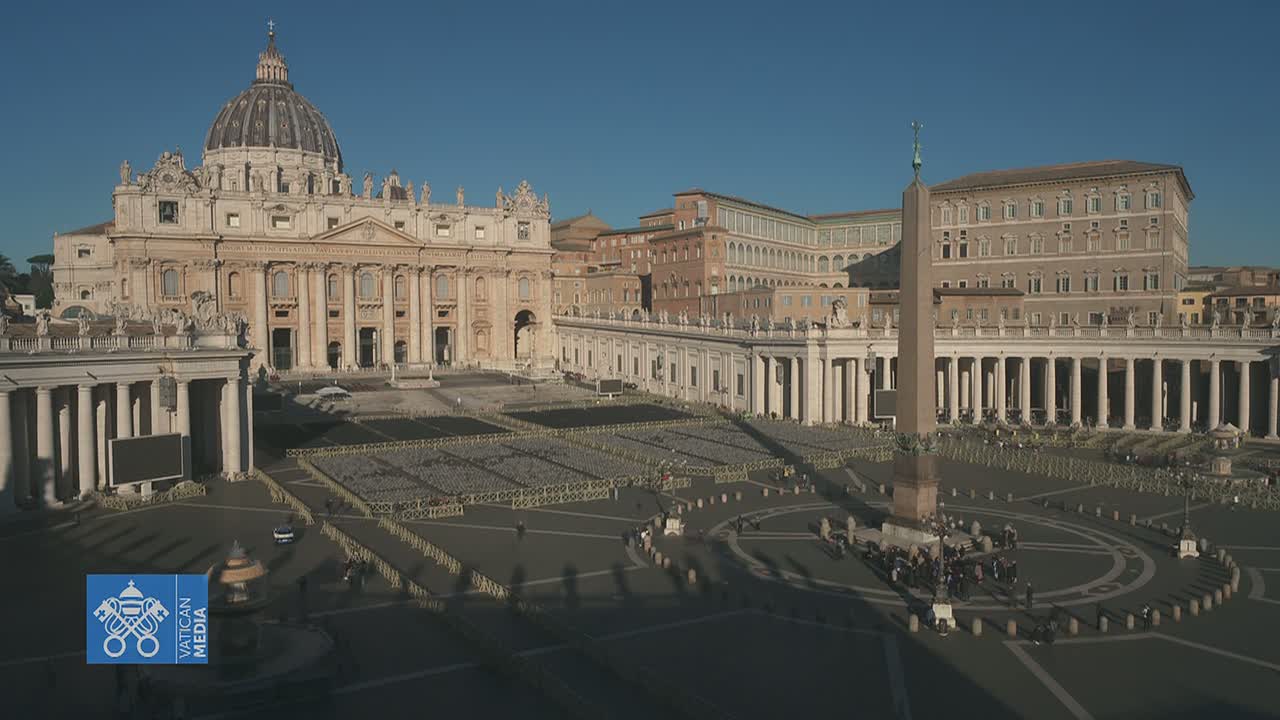 St. Peter's Basilica and St. Peter's Square in Vatican City are shown on a sunny day, with rows of chairs set up in the square.