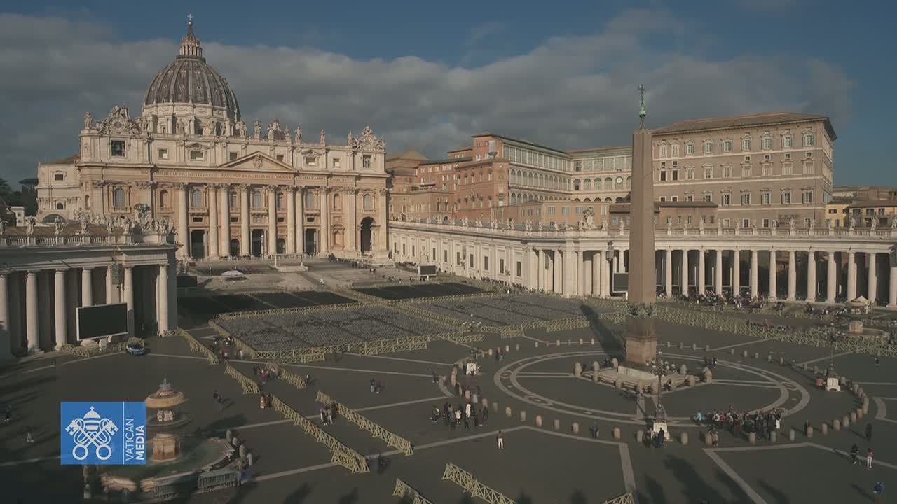 St. Peter's Basilica and Square in Vatican City, under a partly cloudy sky, are shown with many empty chairs set up in the square and a few people scattered throughout.