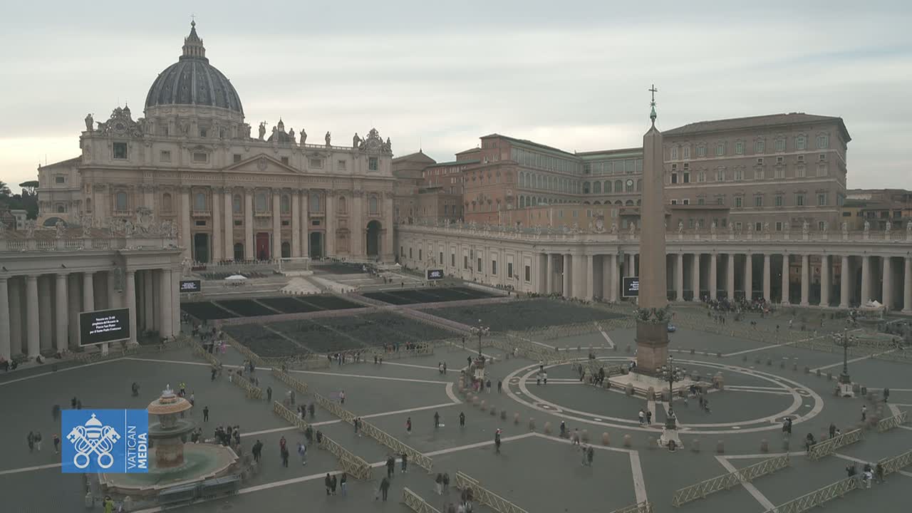 St. Peter's Basilica and St. Peter's Square in Vatican City on an overcast day, with a sparse crowd of people throughout the plaza.