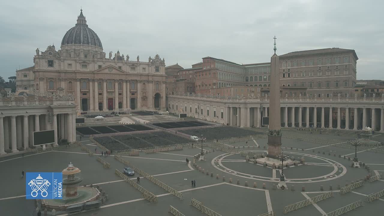 A mostly empty St. Peter's Square in Vatican City is shown on an overcast day, with St. Peter's Basilica and other buildings visible in the background.
