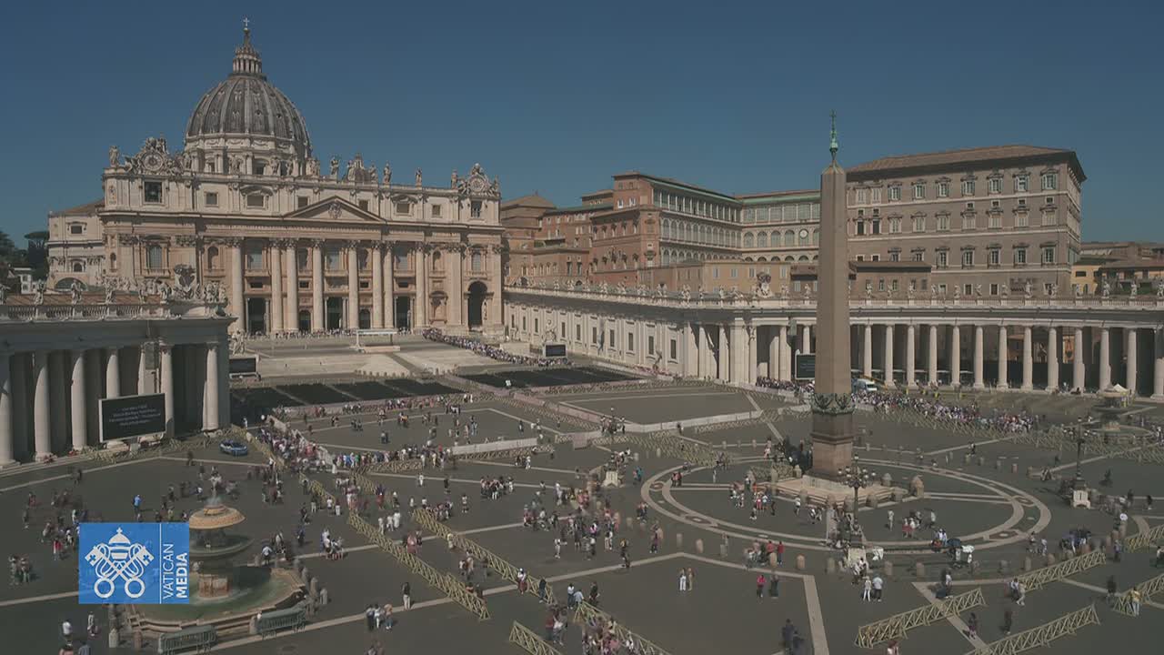 A large crowd of people gathers in St. Peter's Square in front of St. Peter's Basilica on a sunny day.