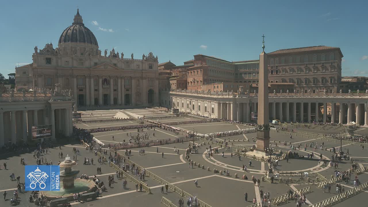 A large crowd gathers in St. Peter's Square in front of St. Peter's Basilica on a sunny day.