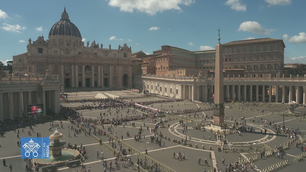 A large crowd gathers in St. Peter's Square in front of St. Peter's Basilica on a sunny day.