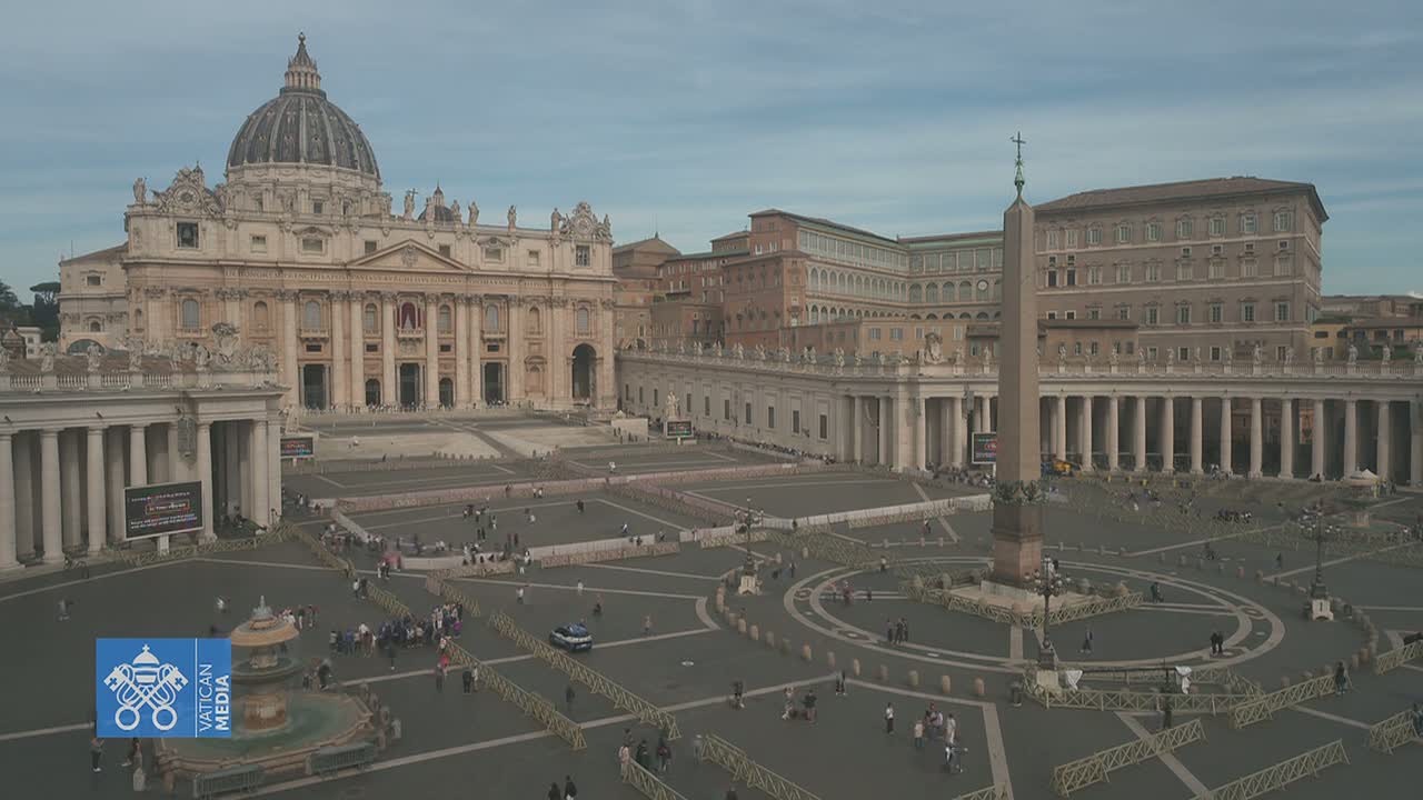 A large, mostly empty plaza with St. Peter's Basilica and an obelisk in the background under a cloudy sky.