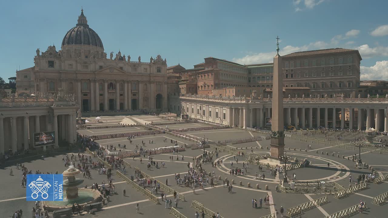 St. Peter's Basilica and St. Peter's Square are shown on a sunny day, with many people gathered in the square.