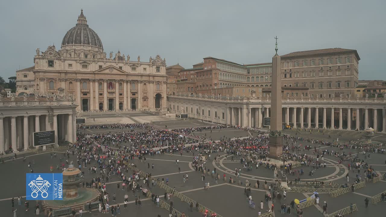 A large crowd of people gathers in St. Peter's Square in front of St. Peter's Basilica on an overcast day.