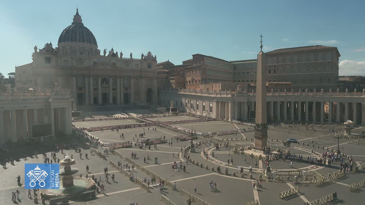 A large, mostly empty plaza with St. Peter's Basilica and other buildings in the background on a sunny day.