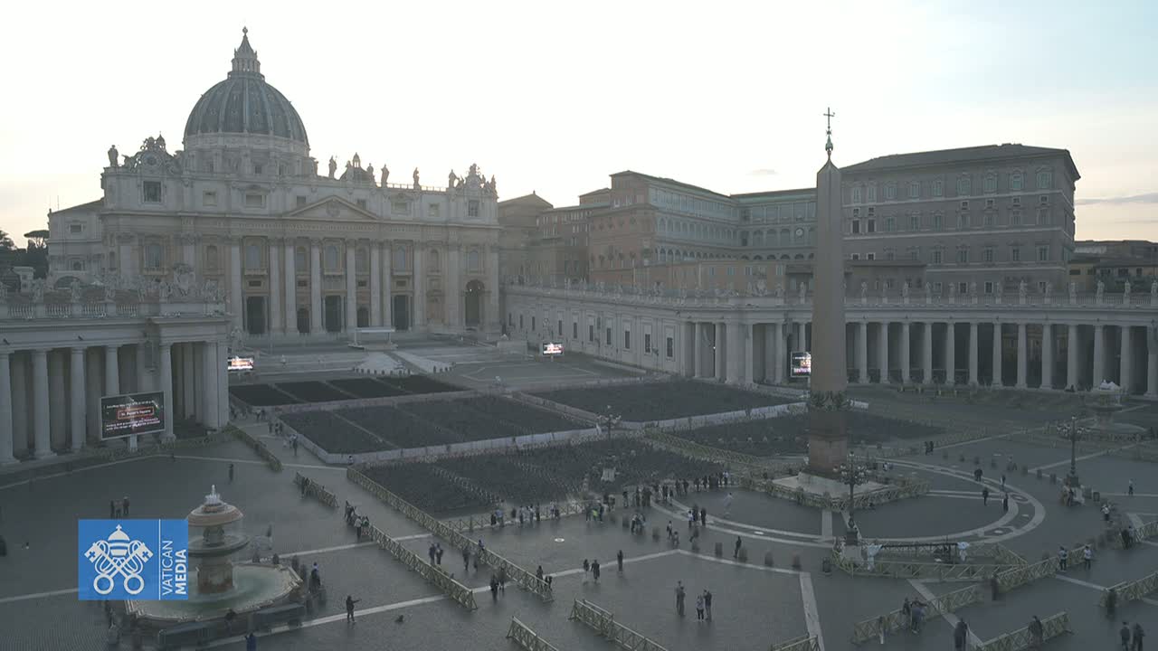 St. Peter's Basilica and Square in Vatican City are shown on an overcast day with many barriers and a sparse crowd of people.