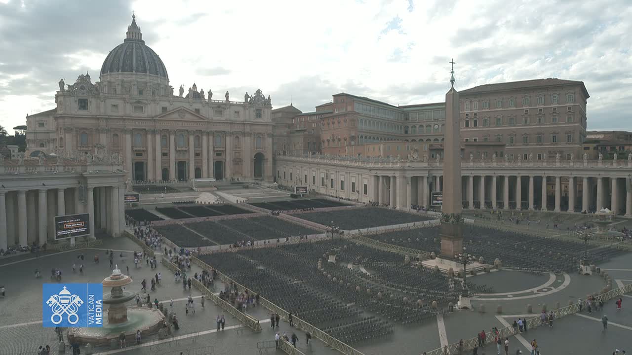 St. Peter's Basilica and Square in Vatican City, under a cloudy sky, are filled with numerous rows of empty chairs and a few people walking around.